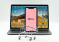 Klarna App open on a mobile phone placed inside a small shopping trolley, with the Klarna website open on a laptop in the background.