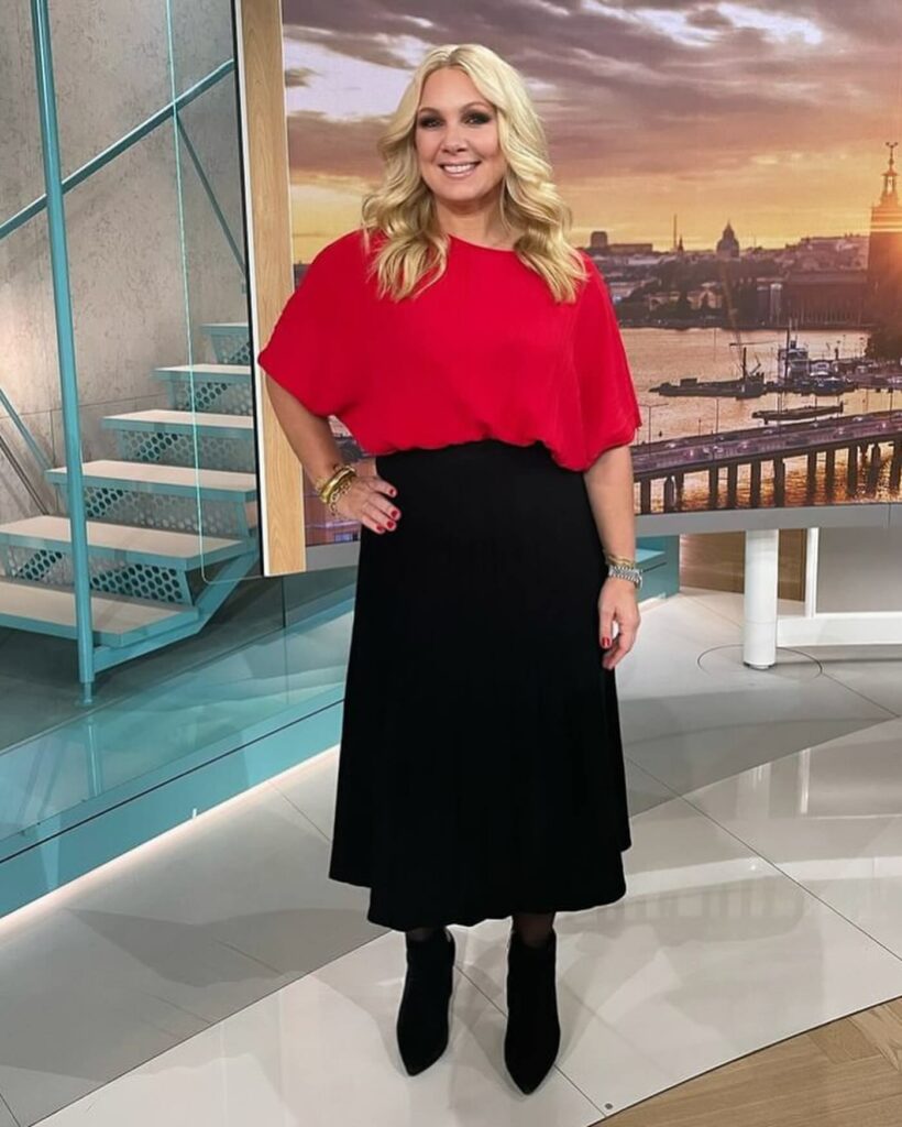 Anna Brolin wearing red top and black skirt.