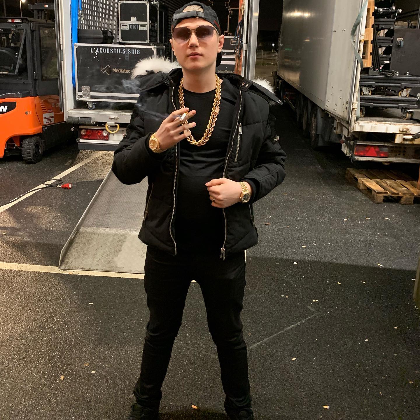 Einar wearing black colored clothes and holding a cigarette in his hand.